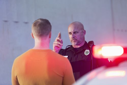 Police officer giving sobriety test to young man to see if he is driving under the influence of drugs or alcohol. - Criminal & DUI Law of Georgia