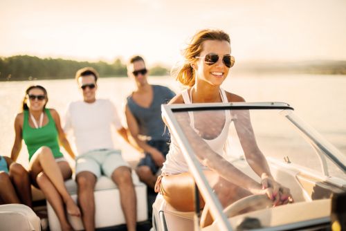 Young woman driving a speedboat with three young people in the background sitting on the edge of the boat. - Criminal & DUI Law of Georgia