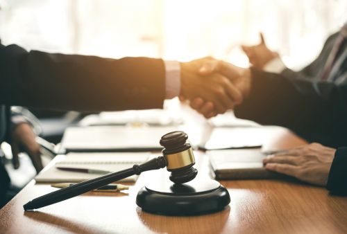 Client and lawyer shaking hands blurry image with gavel in focus