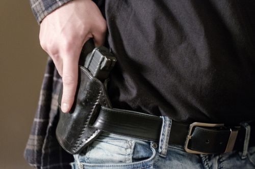 A man drawing his handgun from leather hip gun holder