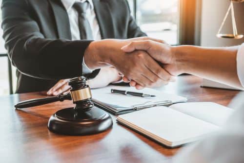 Male lawyer shaking clients hand over papers and gavel.