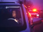 Woman driver pulled over by police car - police lights in background